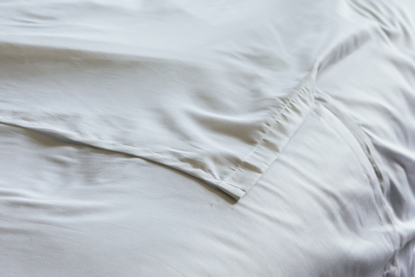 Close-up of the bottom of a white split flat sheet on a bed