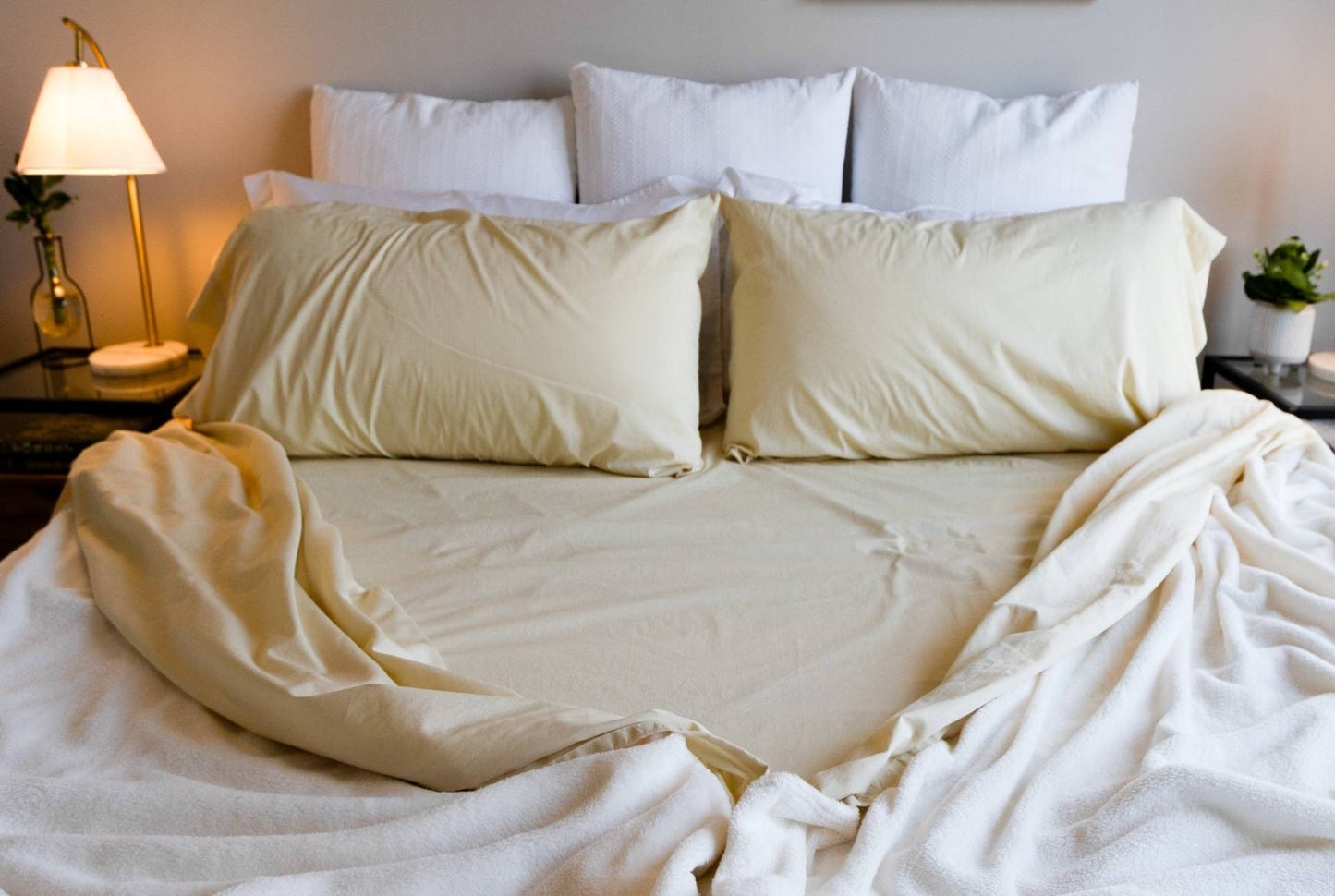 Neatly made bed with cream split bedding and pillows in a bedroom setting.