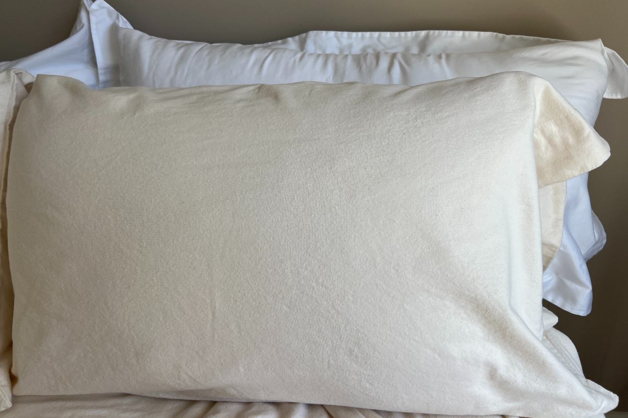 Pillow on a bed with flannel pillowcase and white pillow shams in the background