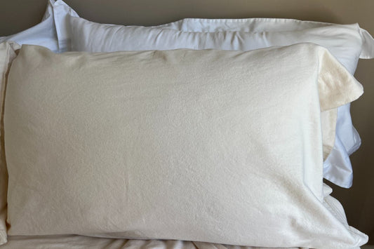 Pillow on a bed with flannel pillowcase and white pillow shams in the background