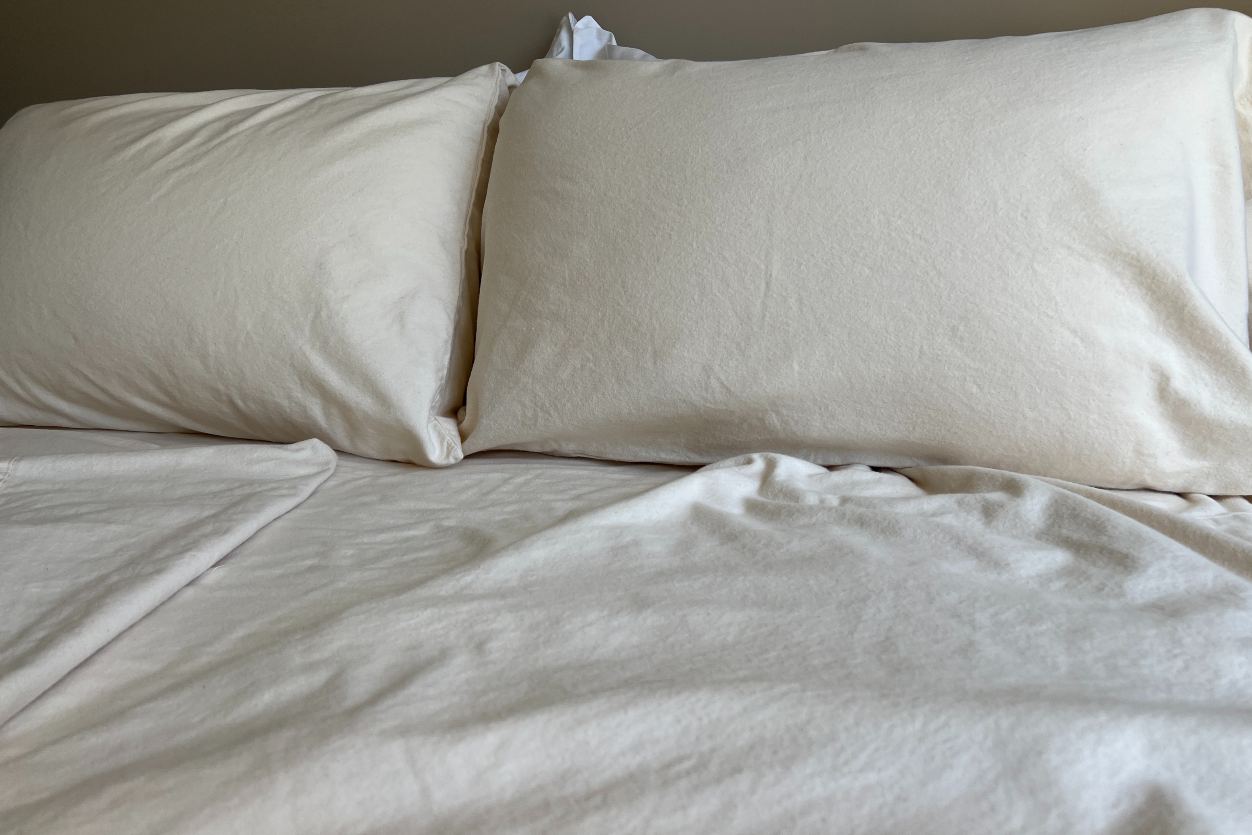 Two pillows on a bed with light flannel bedding.