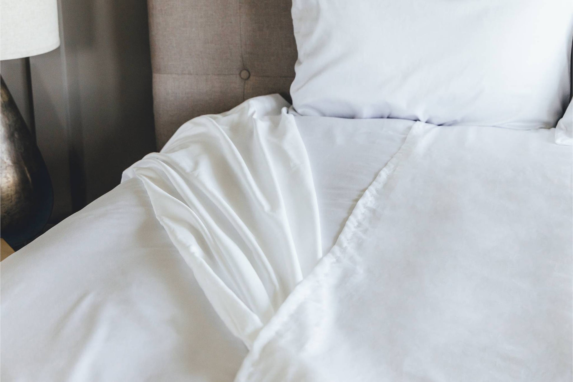 Close-up of a white split sheet on a bed with pillows.