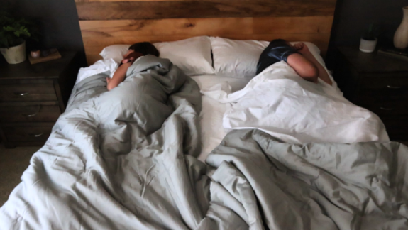 Couple sleeping in bed showcasing split bedding